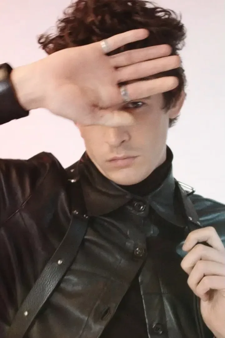 Original frame: a man in a leather jacket shading his eyes