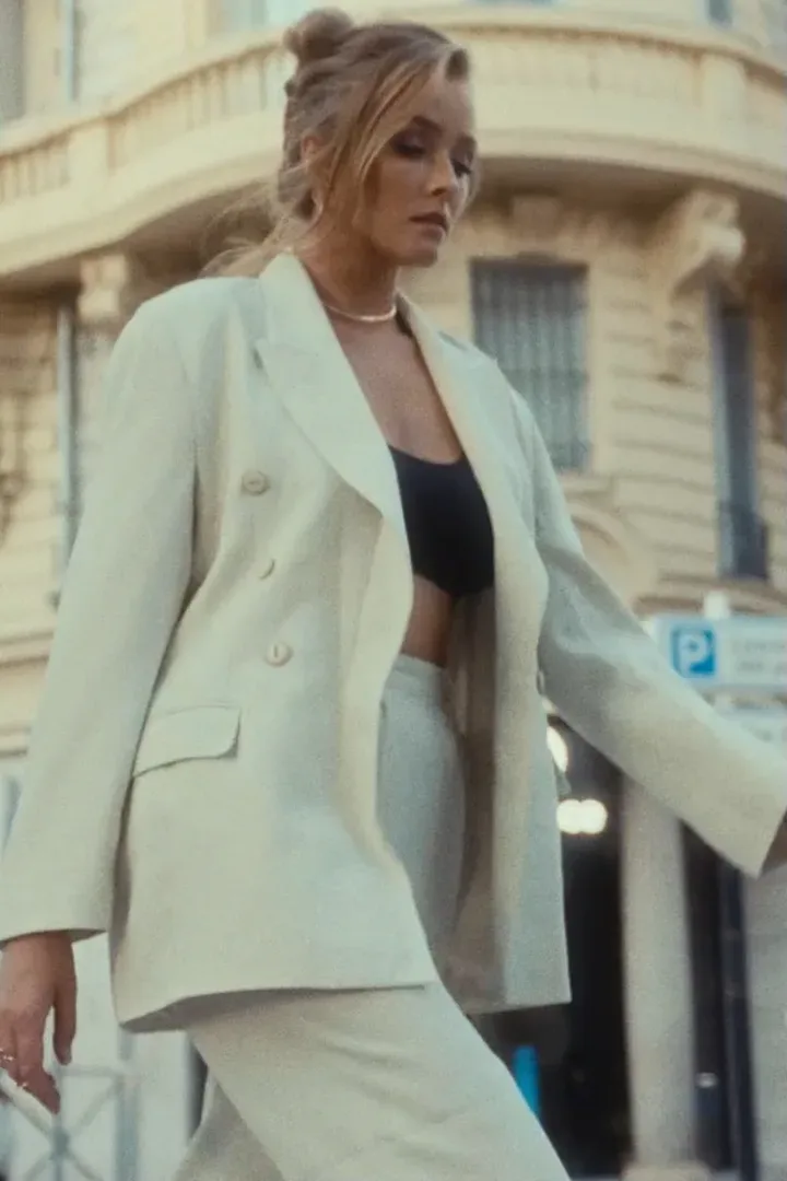 A woman in a white suit on a city street, cut through STAGO looks